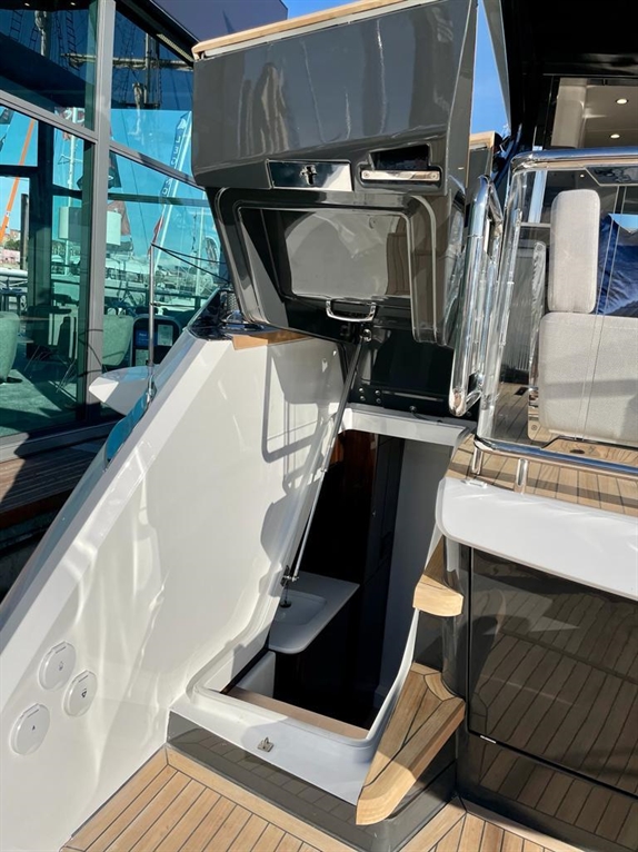 A sleek boat features an open compartment revealing a small interior space with a toilet, surrounded by modern finishes.